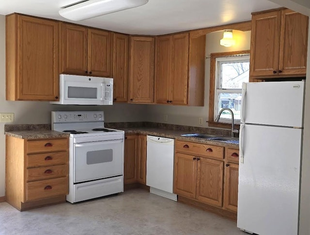 kitchen featuring dark countertops, a sink, white appliances, brown cabinetry, and light floors