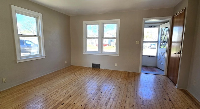 empty room with visible vents, baseboards, and hardwood / wood-style flooring
