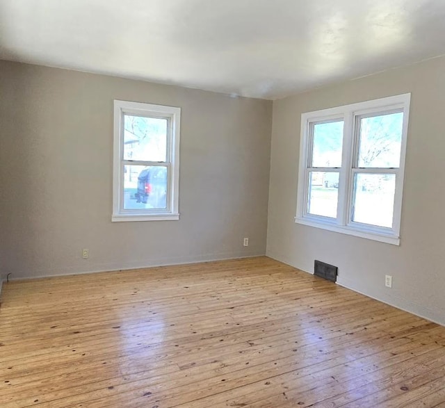 empty room with light wood-type flooring and visible vents
