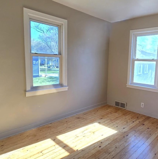 empty room featuring visible vents and hardwood / wood-style floors