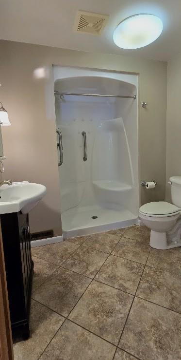 full bath with visible vents, tile patterned flooring, a shower stall, vanity, and toilet