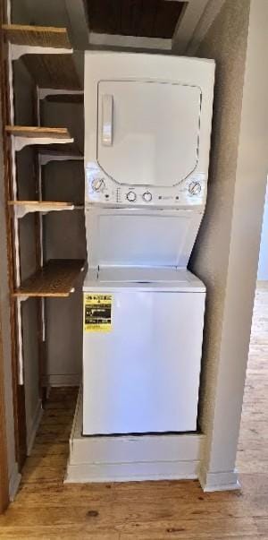 clothes washing area with laundry area, stacked washer and clothes dryer, and light wood finished floors