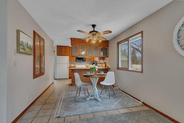 dining space featuring baseboards, a ceiling fan, a textured ceiling, and light tile patterned flooring