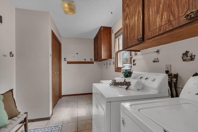 laundry room featuring light tile patterned flooring, baseboards, a textured ceiling, washing machine and clothes dryer, and cabinet space