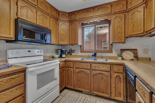 kitchen featuring a sink, brown cabinetry, black appliances, and light tile patterned flooring