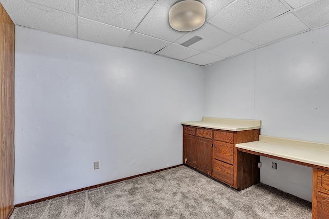unfurnished office with light colored carpet, a paneled ceiling, built in study area, and visible vents