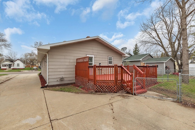 back of house with concrete driveway, a gate, a wooden deck, and fence