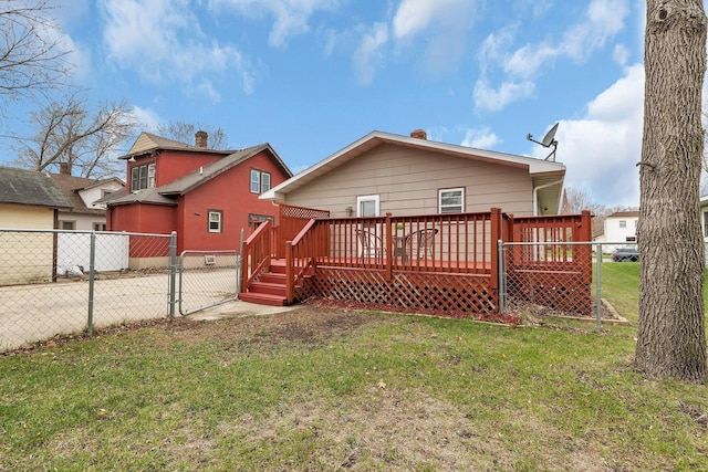 back of property featuring fence, a deck, a gate, concrete driveway, and a yard