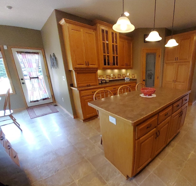 25124 Firefly Ave, Wyoming, MN 55092 - kitchen featuring brown cabinets, glass insert cabinets, a center island, decorative light fixtures, and light flooring
