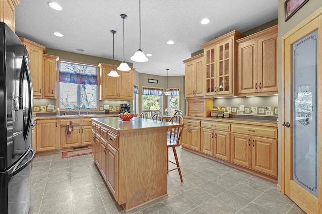 25124 Firefly Ave, Wyoming, MN 55092 - kitchen featuring black refrigerator with ice dispenser, recessed lighting, a breakfast bar area, a center island, and glass insert cabinets
