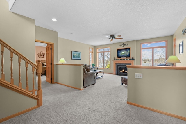 25124 Firefly Ave, Wyoming, MN 55092 - carpeted living room with ceiling fan, healthy amount of natural light, a textured ceiling, a warm lit fireplace, and baseboards