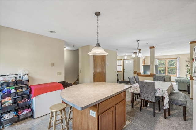 kitchen featuring light countertops, open floor plan, pendant lighting, and a center island