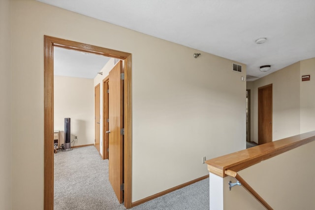hallway with baseboards, light carpet, and visible vents