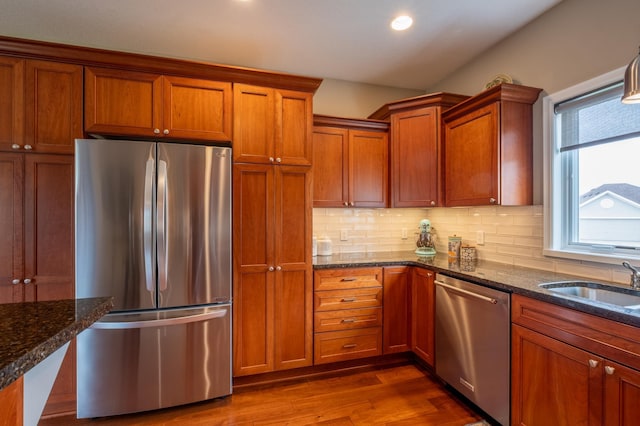 kitchen featuring brown cabinets, stainless steel appliances, decorative backsplash, and a sink