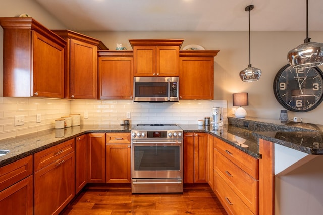kitchen with a peninsula, dark wood finished floors, decorative backsplash, and appliances with stainless steel finishes