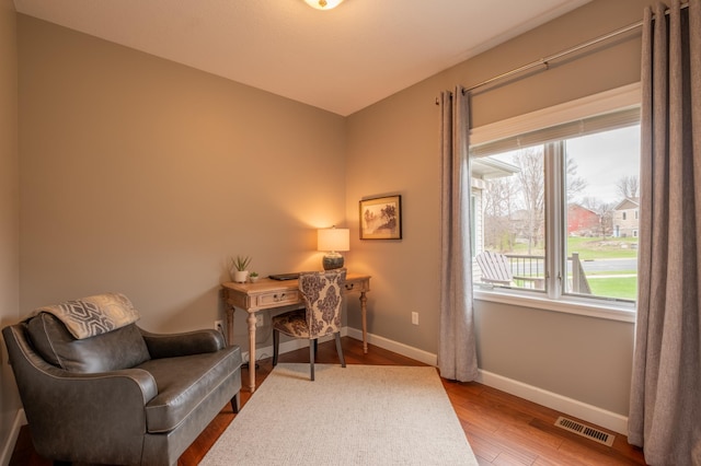 office area with baseboards, visible vents, and wood finished floors