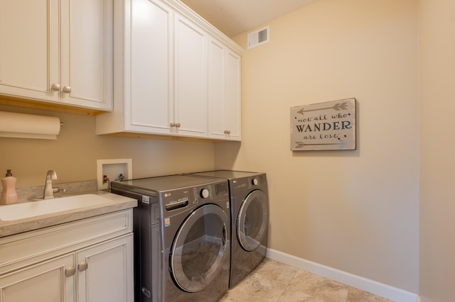 washroom featuring a sink, cabinet space, visible vents, washer and dryer, and baseboards