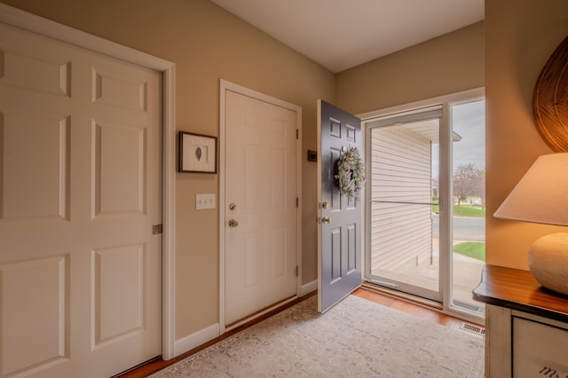 foyer entrance with light wood-style flooring and baseboards