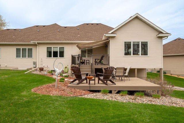 rear view of house featuring a lawn, roof with shingles, and a wooden deck