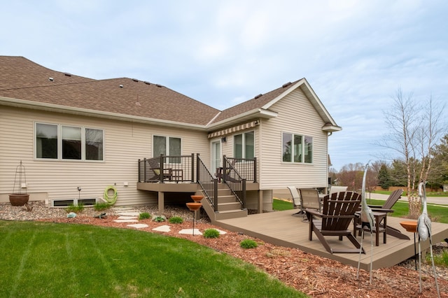 rear view of property featuring a lawn, a wooden deck, and roof with shingles