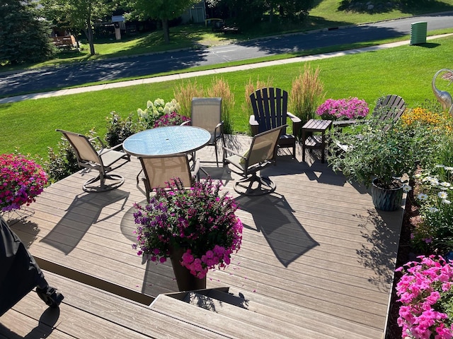 wooden terrace with a lawn and outdoor dining space