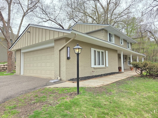 view of front of property featuring a garage, board and batten siding, driveway, and brick siding