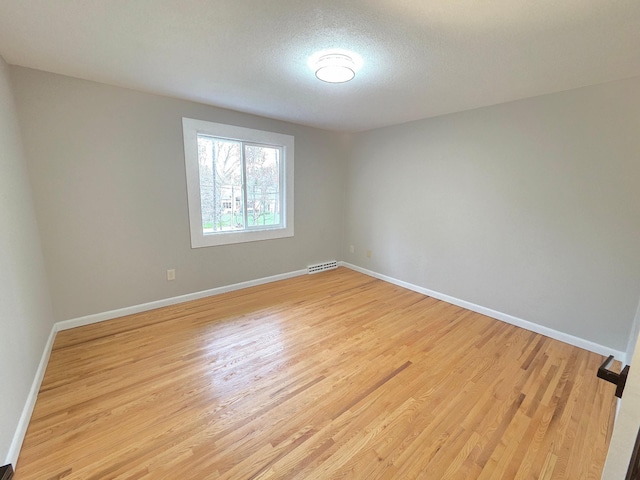 spare room featuring visible vents, light wood finished floors, and baseboards