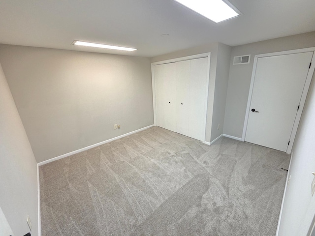 unfurnished bedroom with baseboards, visible vents, light carpet, and a closet