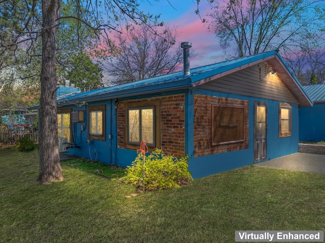 property exterior at dusk with a lawn and metal roof