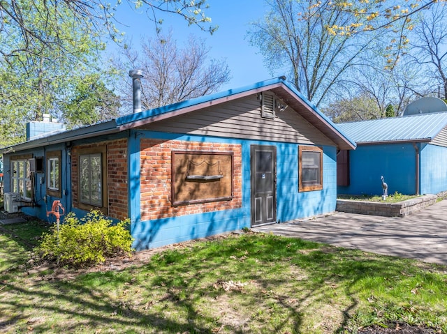 view of front of home featuring metal roof, a patio, a chimney, and a front yard