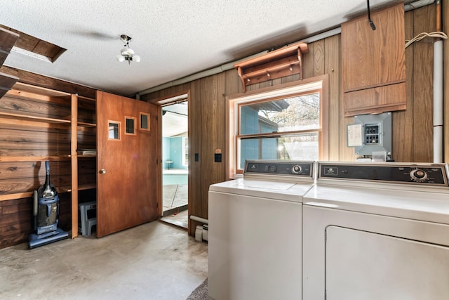 clothes washing area featuring washing machine and clothes dryer, wooden walls, laundry area, and a textured ceiling