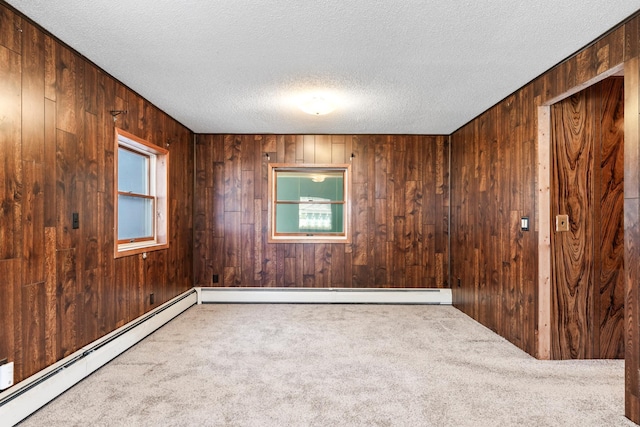 unfurnished room with a textured ceiling, wooden walls, baseboard heating, and carpet