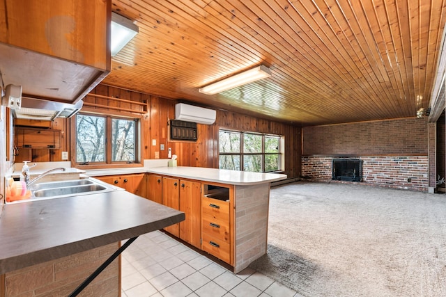 kitchen featuring a peninsula, a wall mounted air conditioner, a wealth of natural light, and a sink