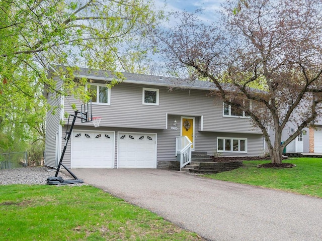 raised ranch with fence, driveway, a front yard, and a garage