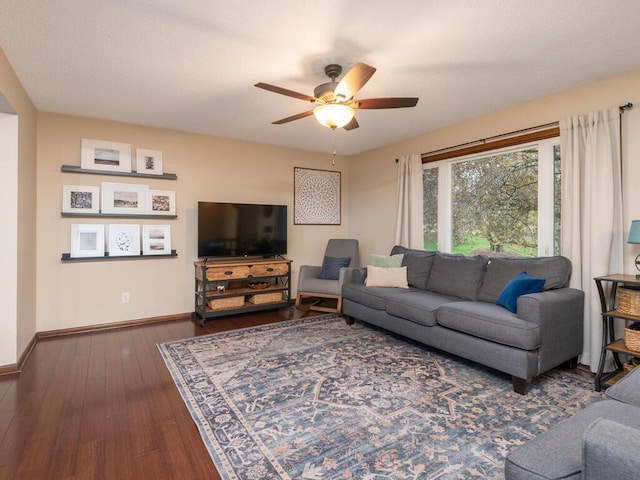 living room featuring dark wood-type flooring, baseboards, and ceiling fan