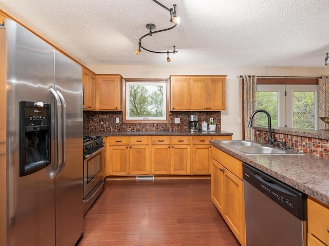 kitchen featuring a sink, a textured ceiling, stainless steel appliances, decorative backsplash, and a wealth of natural light