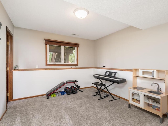 recreation room with a sink, carpet floors, and baseboards