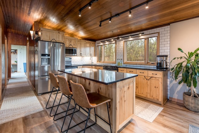 kitchen with track lighting, a sink, dark countertops, and stainless steel appliances