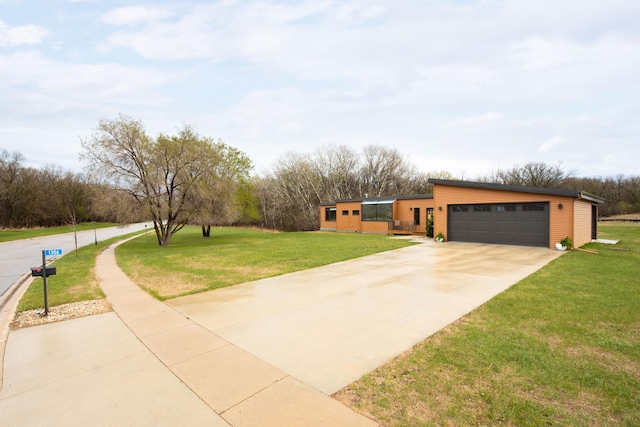 view of front of home with an attached garage, driveway, and a front lawn