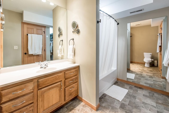 bathroom with baseboards, stone finish floor, toilet, and visible vents