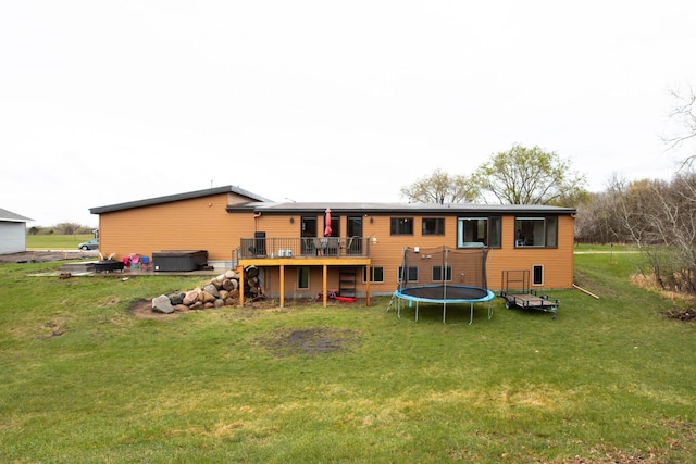 back of house with a lawn, a wooden deck, and a trampoline