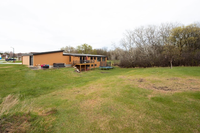 view of yard with a wooden deck and a trampoline