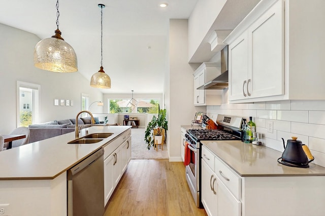 10725 Knollwood Ln, Woodbury, MN 55129 - kitchen featuring stainless steel appliances, a sink, open floor plan, light wood-style flooring, and wall chimney exhaust hood