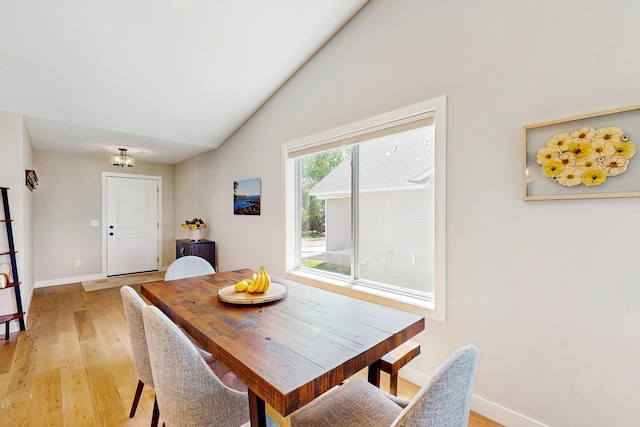 10725 Knollwood Ln, Woodbury, MN 55129 - dining room featuring light wood finished floors, lofted ceiling, baseboards, and a chandelier