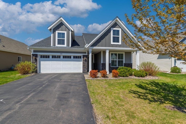 view of front of home with board and batten siding, stone siding, asphalt driveway, and a front lawn