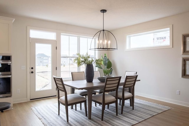 10451 Blackmoor Rd, Woodbury, MN 55129 - dining room featuring baseboards, a chandelier, and light wood-style floors