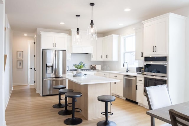 10451 Blackmoor Rd, Woodbury, MN 55129 - kitchen featuring a center island, light wood-style flooring, appliances with stainless steel finishes, and a kitchen bar