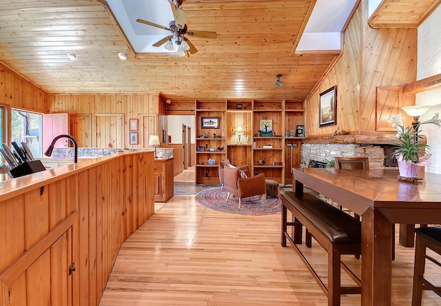 6575 145th St E, Cannon City Twp, MN 55057 - dining room with a fireplace, ceiling fan, wooden walls, light wood-style flooring, and wood ceiling