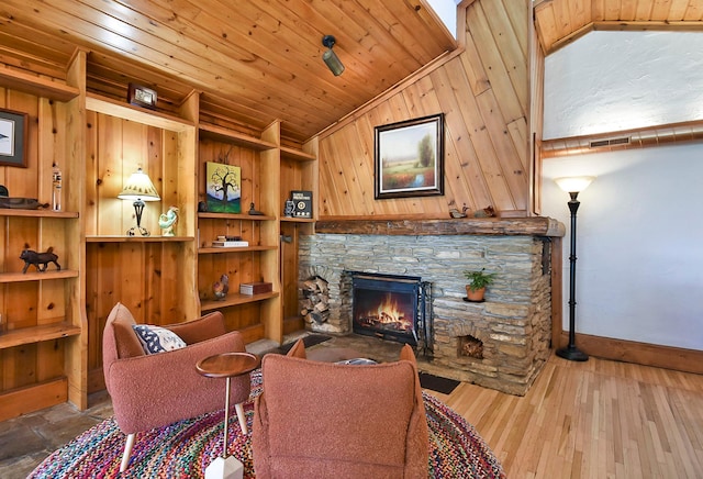 6575 145th St E, Cannon City Twp, MN 55057 - living area with lofted ceiling, baseboards, a stone fireplace, visible vents, and wooden walls