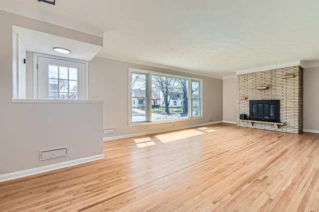 unfurnished living room featuring light wood-type flooring, healthy amount of natural light, and baseboards